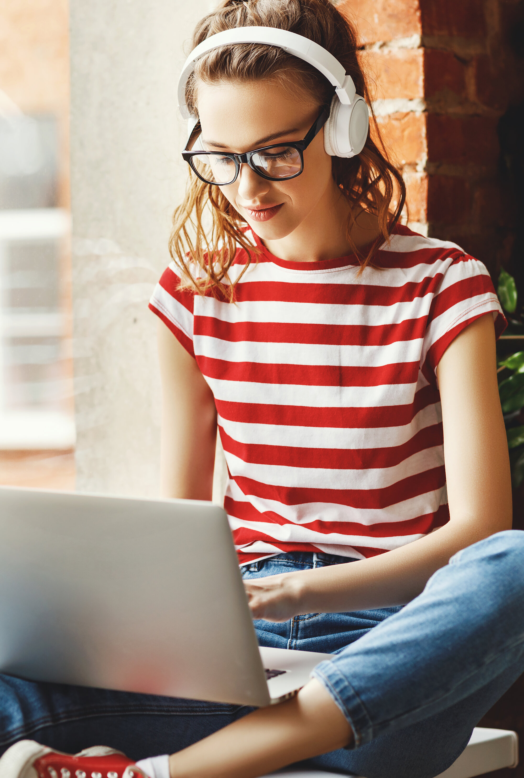 Teenager sitzt mit Kopfhörer vor einem Laptop